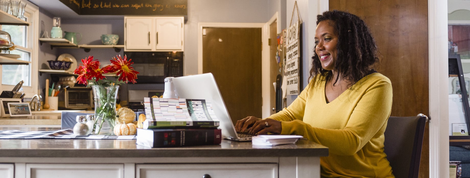 Adult female student typing on a laptop at a kitchen table