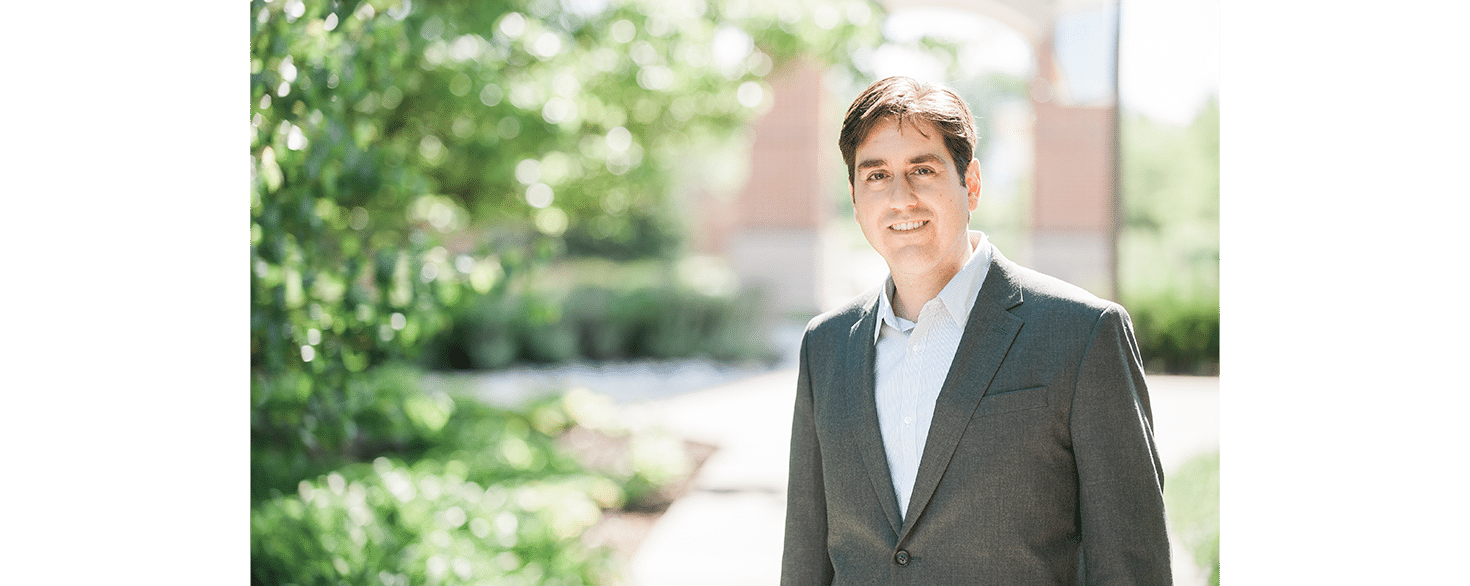 Dr. Michael Pasquale standing on sidewalk in front of Cornerstone University's Welch Clock Tower