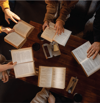Aerial view of open Bibles in circle around a wooden table