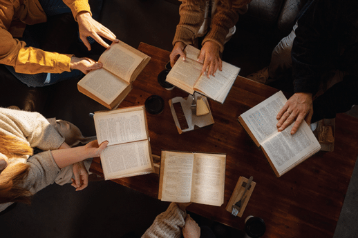 Aerial view of open Bibles in circle around a wooden table