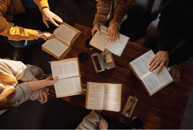 Aerial view of open Bibles in circle around a wooden table
