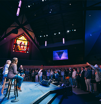 Worship band performing on stage as a large congregation sings