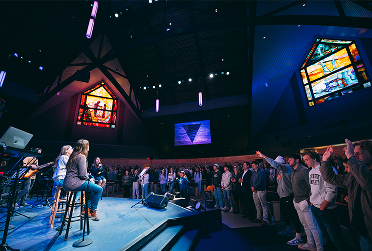 Worship band performing on stage as a large congregation sings
