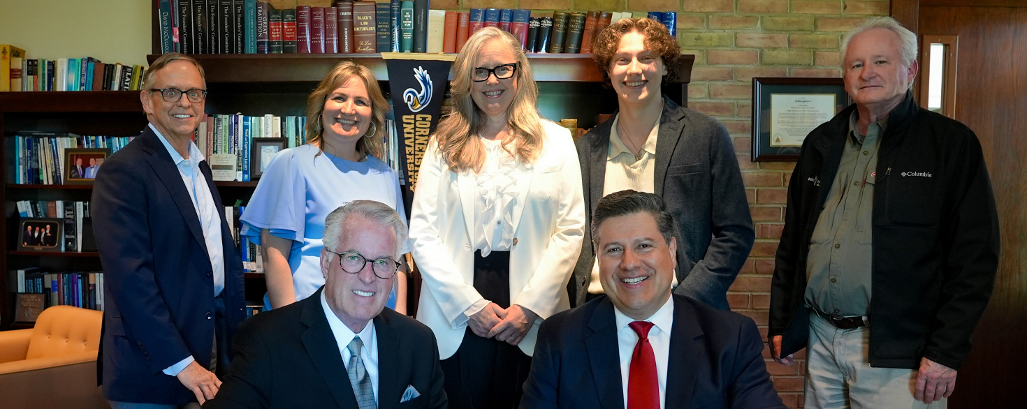 Administrators and family members gather around a desk for a contract signing ceremony with Dr. Gerson Moreno-Riaño, president of Cornerstone University, in the President's Office.