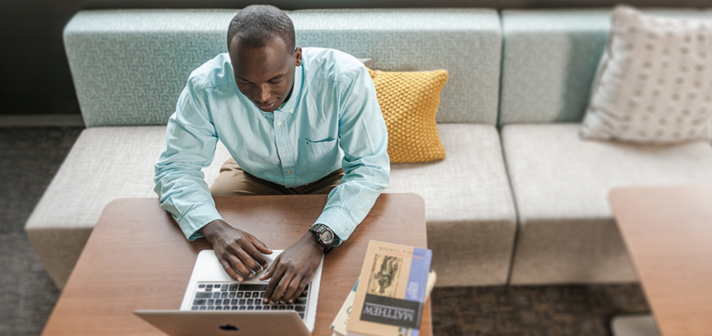 Student researching bible on computer