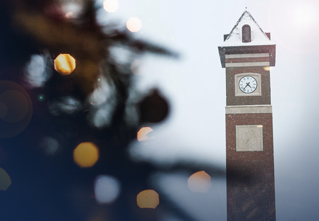 Cornerstone University bell tower in the falling snow with a Christmas tree in the foreground