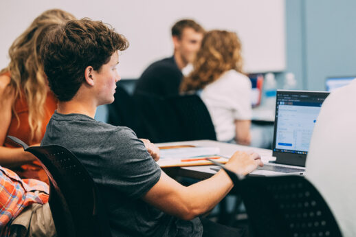 Male student typing on laptop in classroom at Cornerstone University in Grand Rapids, Michigan