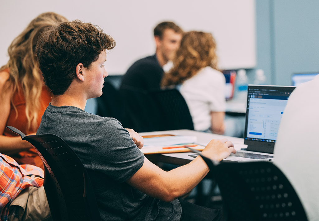 Male student typing on laptop in classroom at Cornerstone University in Grand Rapids, Michigan